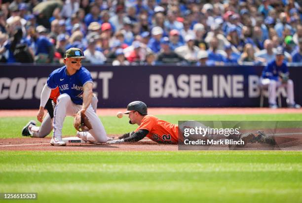 Adam Frazier of the Baltimore Orioles slides in safely for a triple against Matt Chapman of the Toronto Blue Jays in the second inning during their...