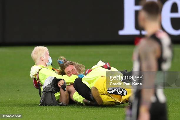 Pitch invader is tackled to the ground by security during the round 7 AFL match between the Geelong Cats and the Collingwood Magpies at Optus Stadium...