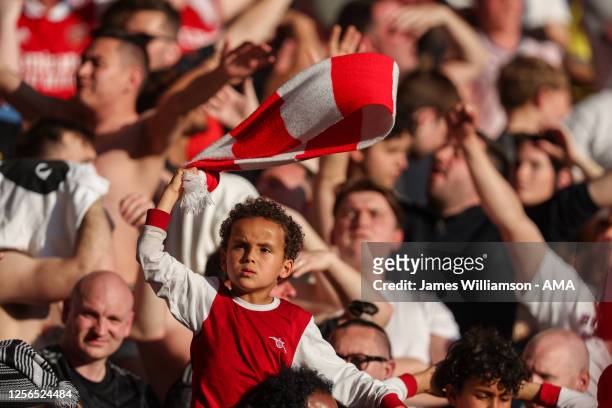 Young fan of Arsenal waving a scarf during the Premier League match between Nottingham Forest and Arsenal FC at City Ground on May 20, 2023 in...