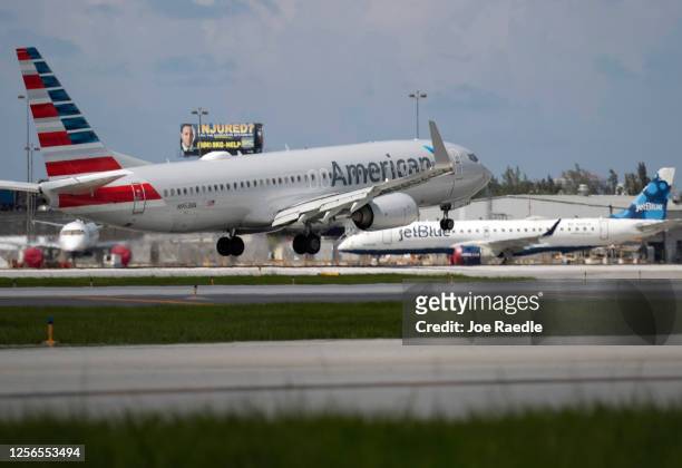 An American Airlines plane lands on a runway near a parked JetBlue plane at the Fort Lauderdale-Hollywood International Airport on July 16, 2020 in...
