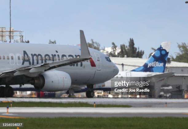 An American Airlines plane takes off near a parked JetBlue plane at the Fort Lauderdale-Hollywood International Airport on July 16, 2020 in Fort...