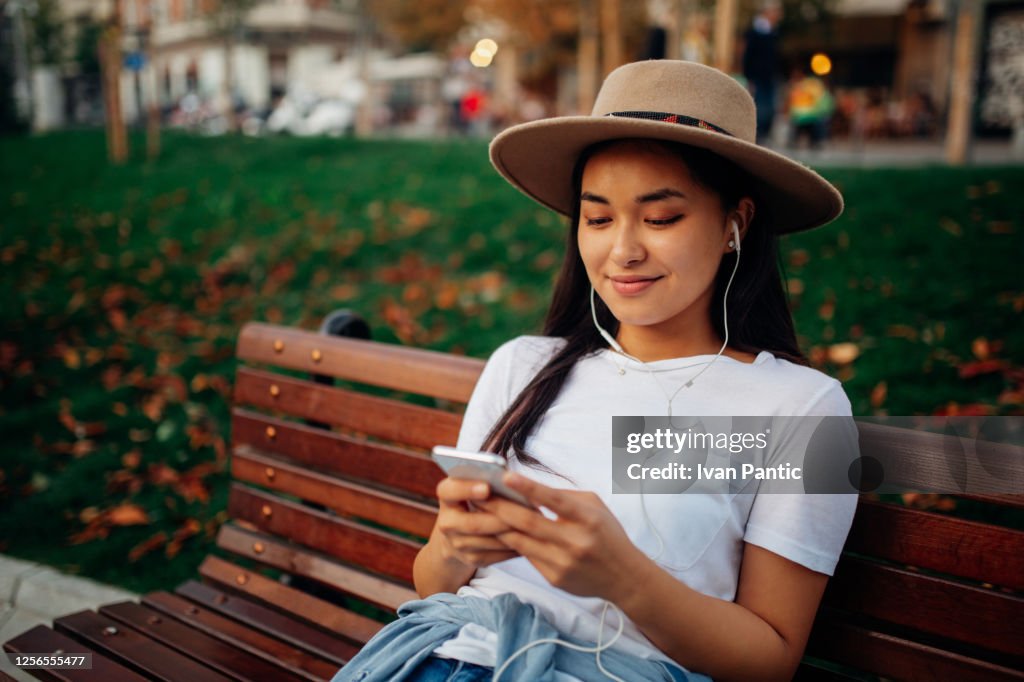 Happy young Asian woman listening to music