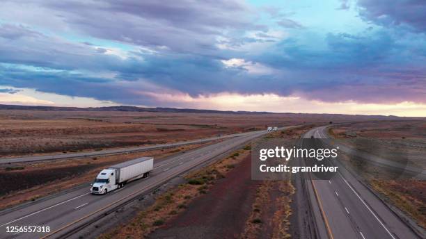 long haul freight hauler semi-truck and trailer traveling on a four-lane highway in a desolate desert at dusk or dawn - refrigerator front stock pictures, royalty-free photos & images