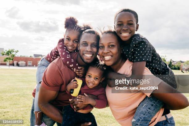 portrait of millennial parents with kids outdoor - african ethnicity stock pictures, royalty-free photos & images