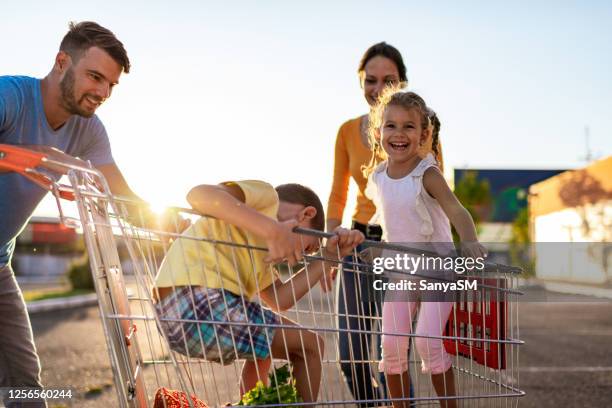 family having fun after grocery shopping - man pushing cart fun play stock pictures, royalty-free photos & images