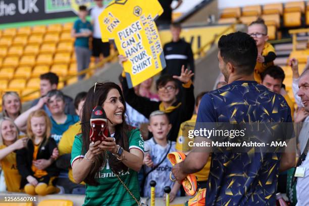 Raul Jimenez of Wolverhampton Wanderers and his girlfriend, Daniela Basso hand out his football boots to the fans during the Premier League match...