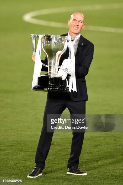 Real Madrid head coach Zinedine Zidane poses with the La Liga trophy after Madrid secure the La Liga title during the Liga match between Real Madrid...