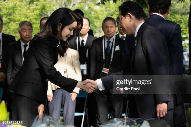 Japan's Prime Minister Fumio Kishida shakes hands with Kim Keon Hee , wife of South Korea's Yoon Suk Yeol, during a visit to the "Monument in Memory...