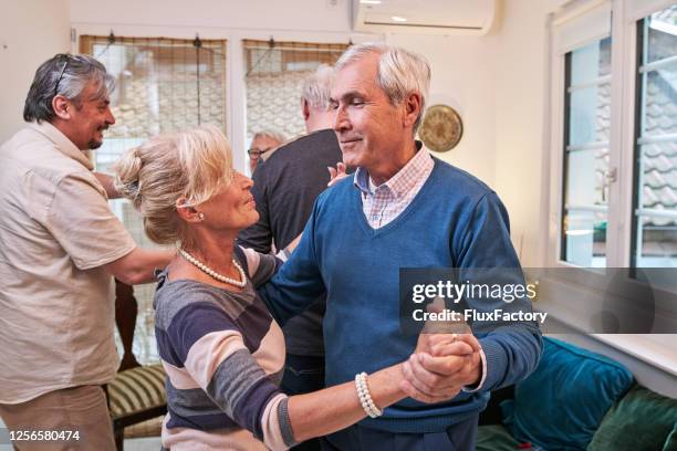 zorgeloos hoger paar dat tango op een partij met vrienden danst - tango stockfoto's en -beelden