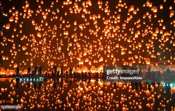 thousands of floating fire paper lanterns in the night sky with reflection in the pool at yee peng festival. loy krathong celebration at sansai, maejo university, chiangmai, thailand - lantern festival bildbanksfoton och bilder