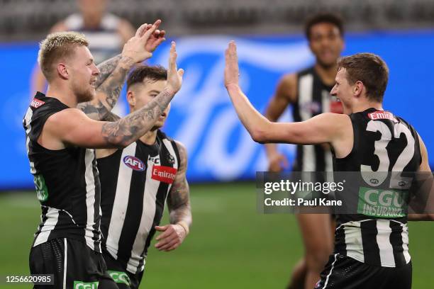 Jordan De Goey of the Magpies celebrates a goal with Jamie Elliott and Will Hoskin-Elliott during the round 7 AFL match between the Geelong Cats and...