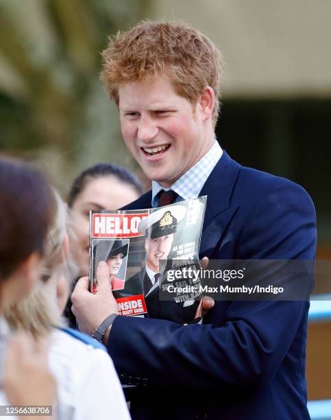 Prince Harry holds up a copy of Hello Magazine as he meets members of the public whilst on a walkabout during a visit to the University Hospital of...