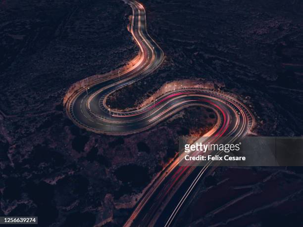 a long exposure of vehicles movement with blurring and light-trails on a winding road during the night. - serpentinen stock-fotos und bilder