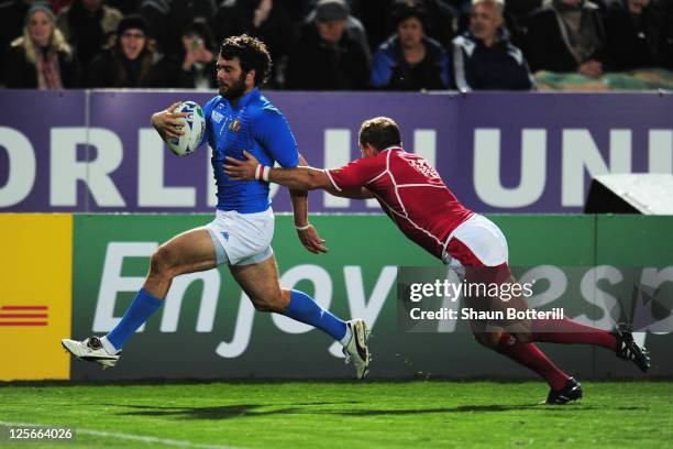 Luke McLean of Italy scores their seventh try despite the challenge of Konstantin Rachkov of Russia during the IRB 2011 Rugby World Cup Pool C match...