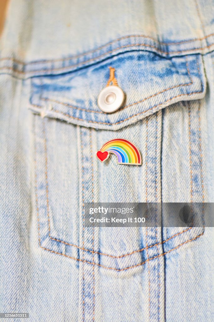 Close-up of a heart rainbow badge on denim jacket pocket