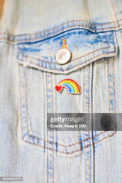 close-up of a heart rainbow badge on denim jacket pocket - brooch pin stock pictures, royalty-free photos & images