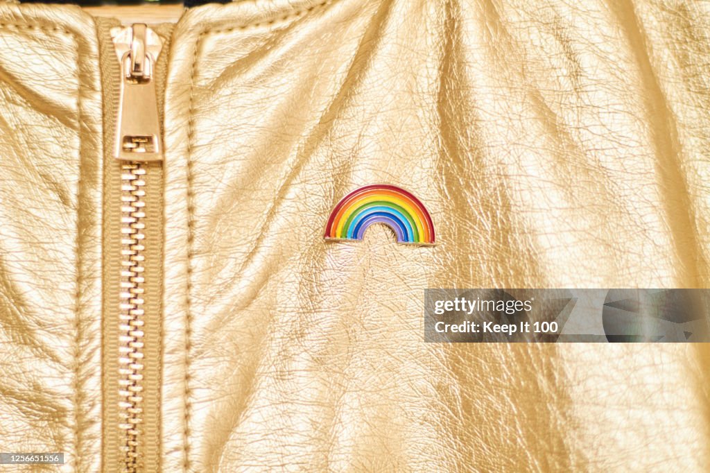 Close-up of a rainbow badge on metallic gold jacket