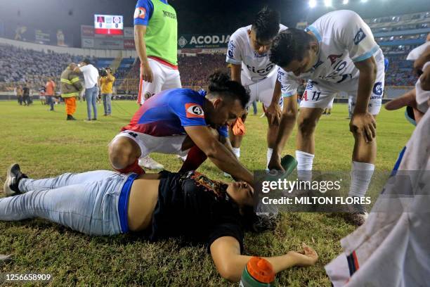 Graphic content / Alianza's players attend an injured fan lying on the pitch following a stampede during a football match between Alianza and FAS at...