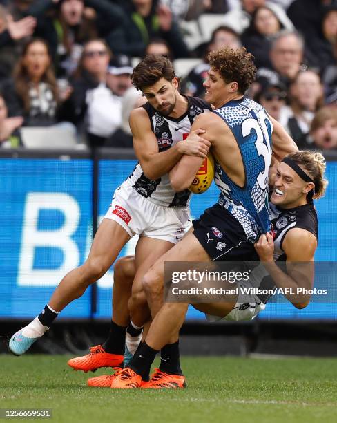 Charlie Curnow of the Blues is tackled by Josh Daicos of the Magpies and Darcy Moore of the Magpies during the 2023 AFL Round 10 match between the...