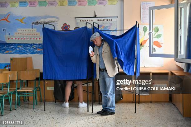 Man holds his ballot as he votes at a polling station during the general election in Athens on May 21, 2023. Greece votes in a general election that...