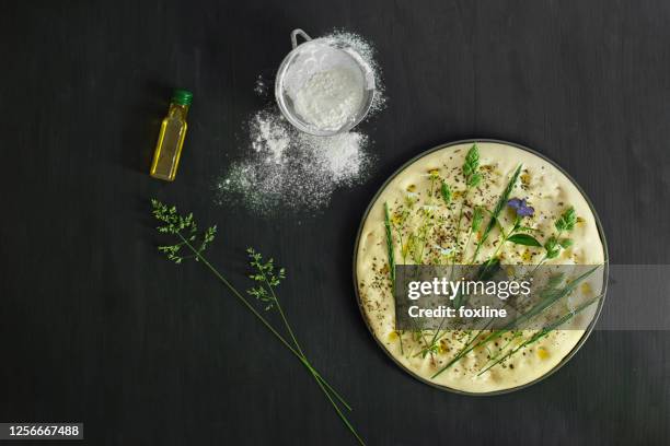 preparing a garden flatbread with wildflowers, grasses and herbs - fougasse photos et images de collection