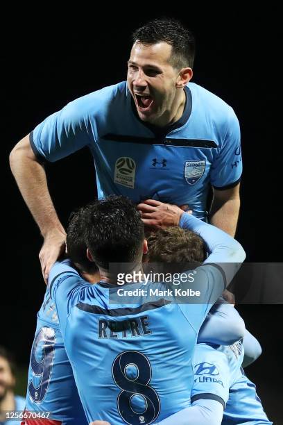 Ryan McGowan of Sydney FC jumps on his team mates as they congratulate Trent Buhagiar of Sydney FC as he celebrates scoring a goal during the round...