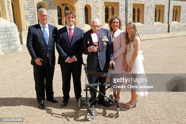 Captain Sir Thomas Moore poses with his family after being awarded with the insignia of Knight Bachelor by Queen Elizabeth II at Windsor Castle on...