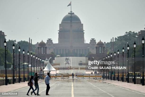 Commuters walk through a mirage on a hot summer day in front of India's presidential palace Rashtrapati Bhavan in New Delhi on May 21, 2023.