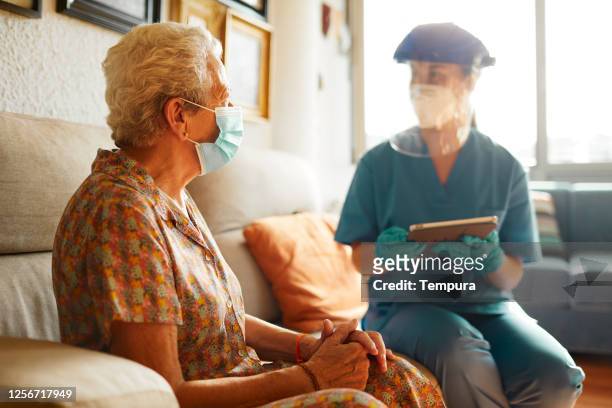 una dottoressa visita una donna anziana nella casa di cura. - abbigliamento da lavoro foto e immagini stock