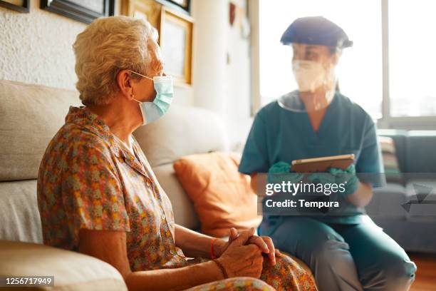 a female doctor visits a senior woman at the nursing home. - aged care mask stock pictures, royalty-free photos & images