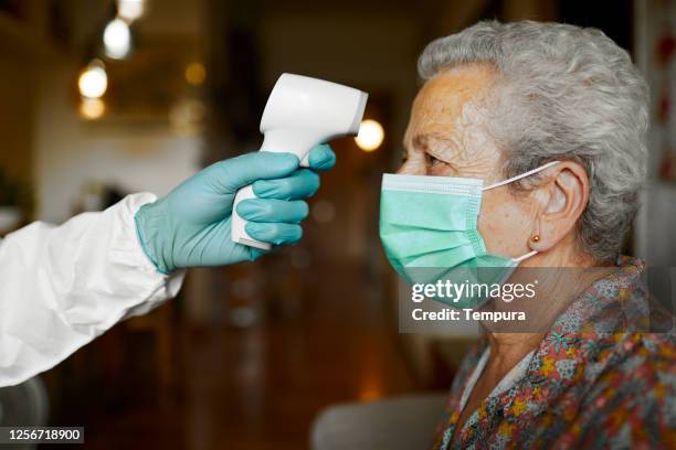 testing for temperature with an infrared thermometer. - aged care covid stock pictures, royalty-free photos & images