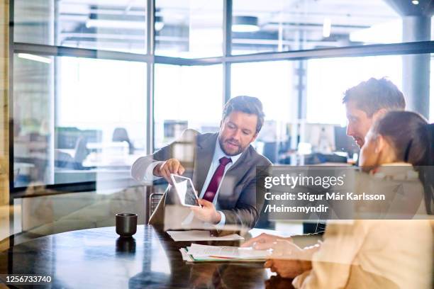 financiële adviseur die met een jong paar in zijn bureau ontmoet - couple at table with ipad stockfoto's en -beelden