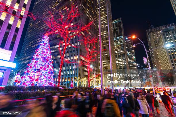 big christmas tree glows among the high-rise buildings in the night at midtown manhattan new york city. - christmas new york stock-fotos und bilder