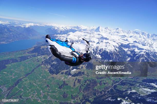 wing suit soars above mountain landscape - water glide stock pictures, royalty-free photos & images