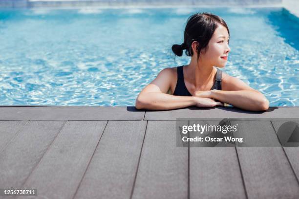 relaxing spa day by the pool in summer - asian woman swimsuit stock-fotos und bilder