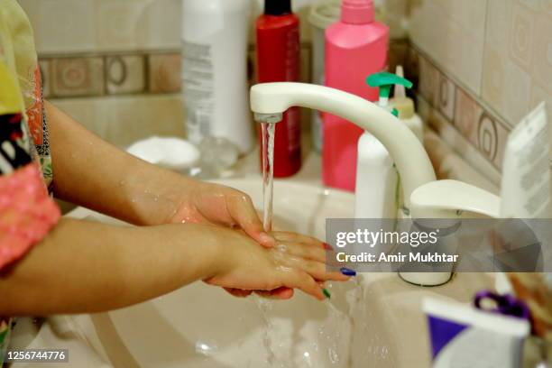 a girl washing her hands with water for hygiene in a domestic washroom. - kids nail art stock pictures, royalty-free photos & images