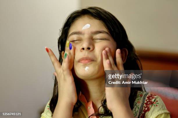 a young girl applying face cream on her face for skincare. - asian massage girl stock-fotos und bilder