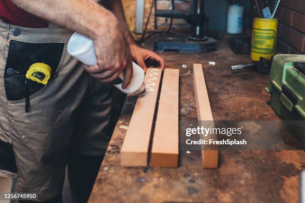 unrecognizabl carpenter applying glue onto planks at his workshop, a close up - colar imagens e fotografias de stock