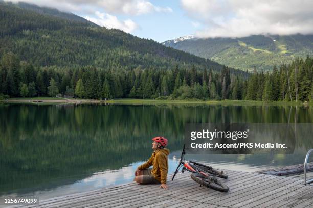 Mountain biker relaxes on lake pier, sunrise
