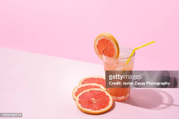 ice cold homemade grapefruit juice on pink background - juice stock pictures, royalty-free photos & images