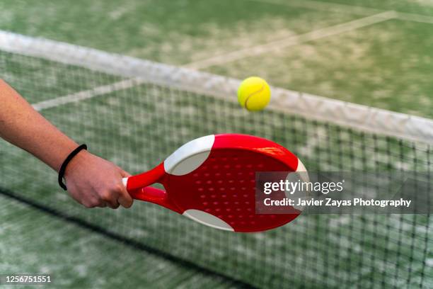 man holding paddle tennis racket about to hit a ball in paddle tennis court - paddle tennis stock pictures, royalty-free photos & images