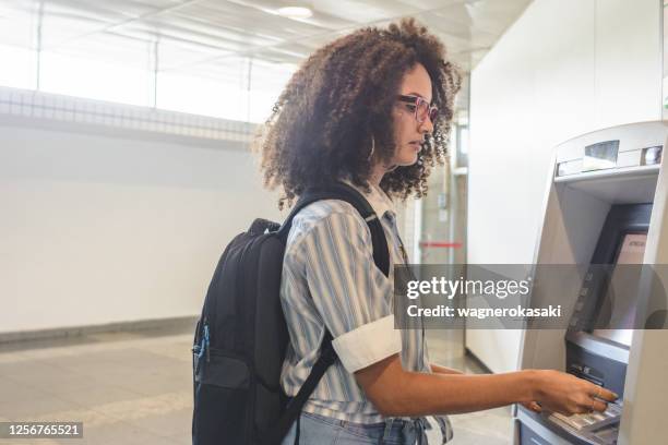 jonge vrouw die geld bij de atm opneemt - bank student stockfoto's en -beelden