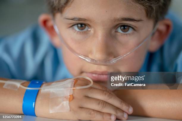 6 year old hispanic boy sitting in hospital with an iv drip - nasal cannula stock pictures, royalty-free photos & images