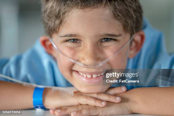 6 year old hispanic boy sitting in hospital with an iv drip - nasal cannula stock pictures, royalty-free photos & images