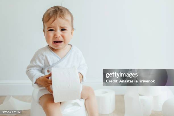 cute hild sitting on white potty and crying. a little girl does not want to write to the chamberpot. sick baby constipation colic, bloating, indigestion heartburn, digestion, pain, diarrhea. - baby pee stock pictures, royalty-free photos & images