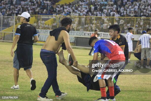 Graphic content / A player and fans help an injured man following a stampede during a football match between Alianza and FAS at Cuscatlan stadium in...