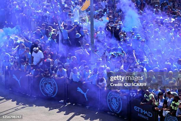 Fans react as they wait for Manchester City's team bus to arrive ahead of the English Premier League football match between Manchester City and...