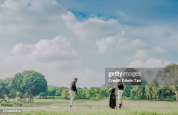 an asian chinese man playing golf tee off while his son watching and learning in melaka golf course malaysia - father son golf stock pictures, royalty-free photos & images