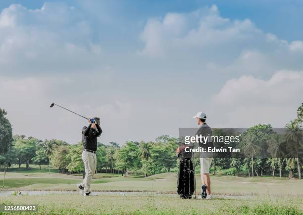 an asian chinese man playing golf tee off while his son watching and learning in melaka golf course malaysia - play off stock pictures, royalty-free photos & images
