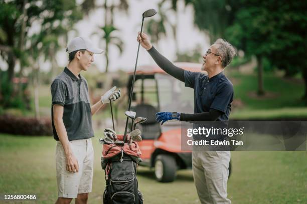 an asian chinese mature adult selecting driver golf club from golf bag for tee off and guiding teaching his son at the golf course tee off point - golf lessons stock pictures, royalty-free photos & images